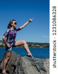 Beautiful adult woman stands on top of rocks with arms out, along Duluth Lakewalk in Canal Park. Concept for triumph, accomplishment, confidence