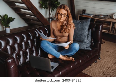 Beautiful adult woman working at home at living room looking through documents, papers, bills, debts, bank loans, mortgage. Businesswoman reading financial report - Powered by Shutterstock