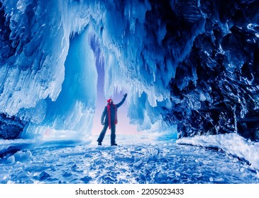 Beautiful Adventure Travel Winter Landscape With People. Tourist Man In Ice Blue Cave Or Grotto On Frozen Lake Baikal.