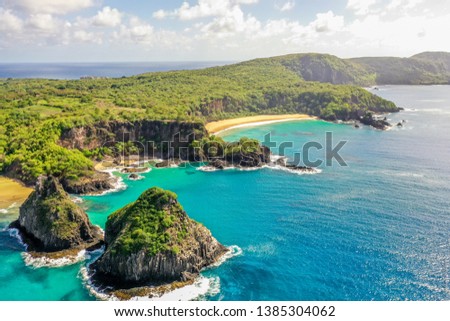Beautiful aerial image of the hill two brothers in fernando de noronha brazil with blue sea, sand, sky, sun and clouds