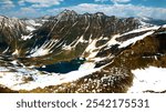 Beautiful aerial photo of lake between snowy and green grass mountains in Azad Kashmir region of Pakistan.