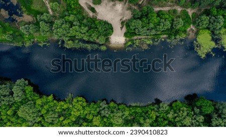 Beautiful aerial shot of an untouched wild river landscape. Gorgeous summer view of a river flowing through the untouched forest. A direct over head drone shot of a wild natural river terrain. 
