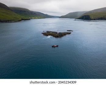 Beautiful aerial view of a boat fishing near the light house in , the sea stacks between the islet Tindholmur in the Faroe Islands - Powered by Shutterstock