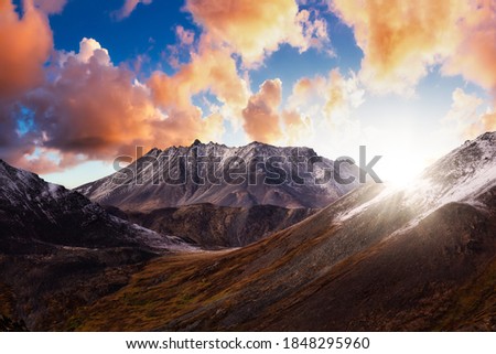 Beautiful Aerial View of Dramatic Mountains and Scenic Alpine Lake during Fall in Canadian Nature. Dramatic Colorful Sunset Artistic Render. Tombstone Territorial Park, Yukon, Canada.