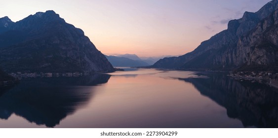 Beautiful aerial view of the famous Como Lake on purple sunset. Mountains reflecting in calm waters of the lake with Alp mountain range on the background. Lombardy, Italy.