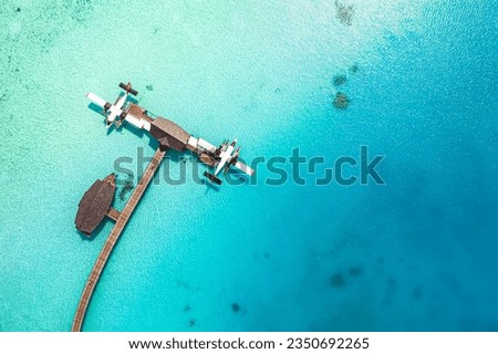 Beautiful aerial view of Maldives coast, pier water villa seaplane top view, wooden boat and tropical beach bay. Turquoise sea water in sunlight. Luxury travel and vacation. Amazing aerial landscape