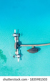 Beautiful aerial view of Maldives jetty seaplane top view with wooden boat Dhoni and tropical beach, jetty over wonderful blue sea. Luxury travel and vacation concept. Amazing aerial landscape