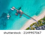 Beautiful aerial view of Maldives shore, jetty villa seaplane top view, wooden boat Dhoni and tropical beach. Palm trees white sand, sea. Luxury travel and vacation concept. Amazing aerial landscape