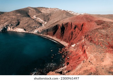 A beautiful aerial view of the Red Beach in Santorini, Greece under a pale sky on a sunny day