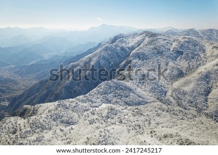 Beautiful aerial view of snow covered pine forests. Rime ice and hoar frost covering trees. Scenic winter landscape of Baizhangling, Lin'an, Hangzhou, Zhejiang, China. Drone landscape in winter.