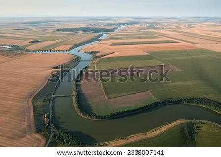 Beautiful aerialview with a country road next to a lake and big agriculture fields. Concept video for summer agriculture and transportation industry.