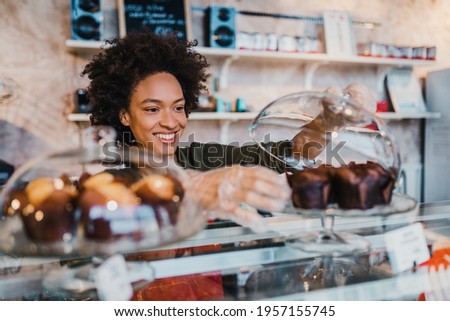 Beautiful African American female worker working in confectionery shop.