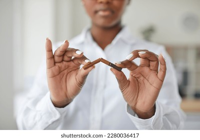 Beautiful African American girl breaking cigarette in half, focus on hands. Cropped shot of young woman in white blouse quitting smoking cigarettes. Stop smoking, health care concept - Powered by Shutterstock