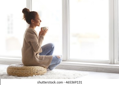 Beautiful African American girl drinking coffee at home