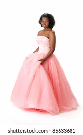 Beautiful African American Haitian Teen Girl Wearing A Pink Strapless Princess Prom Dress. Posing And Smiling On A White Background. Space For Copy.