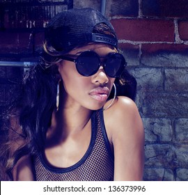 Beautiful African American Model Actress Dancer Wearing Baseball Cap Mesh Top Denim Shorts Standing Beside Graffiti Wall.