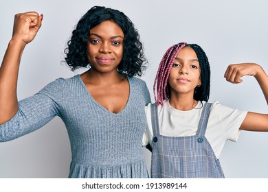 Beautiful African American Mother And Daughter Wearing Casual Clothes And Hugging Strong Person Showing Arm Muscle, Confident And Proud Of Power 