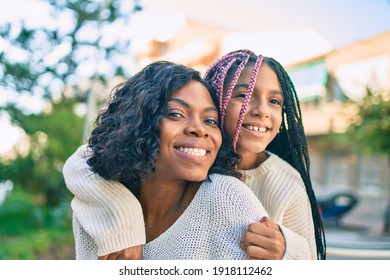 Beautiful african american mother giving daughter piggyback ride smiling happy at the park. - Powered by Shutterstock