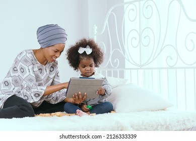 Beautiful African American Mother Playing with Adorable Baby Boy at Home on Living Room Floor. Cheerful Mom Nurturing a Child. Happy Son Raised in the Air. Concept of Childhood, New Life, Parenthood.