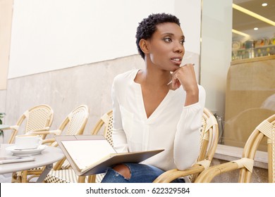 Beautiful African American Professional Business Woman Sitting At Coffee Shop In City Taking Notes With Folder, Thoughtful Outdoors. Freelance Black Female Working In Exterior, Lifestyle.