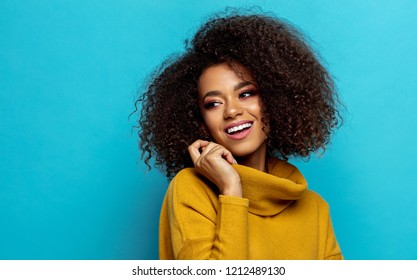 Beautiful african american woman with an afro hairstyle looking on empty space isolated on blue background