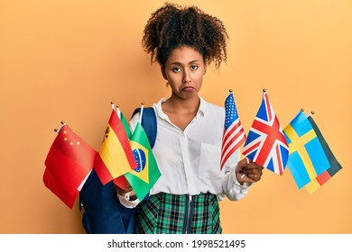 Beautiful African American Woman With Afro Hair Exchange Student Holding Countries Flags Depressed And Worry For Distress, Crying Angry And Afraid. Sad Expression. 