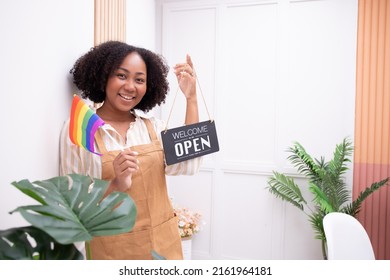 Beautiful African American Woman Business Owner Holding A Store Opening Sign And Holding A Rainbow Flag Supporting LGBTQ+ Gender Equality Bags Homosexuality, Success, Confidence.