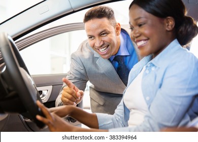 beautiful african american woman buying a car at dealership