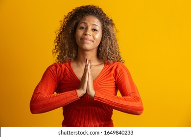 Beautiful African American Woman With Hands Together In Praying Gesture, Expressing Hope And Please Concept. Brazilian Curly Hair Girl.