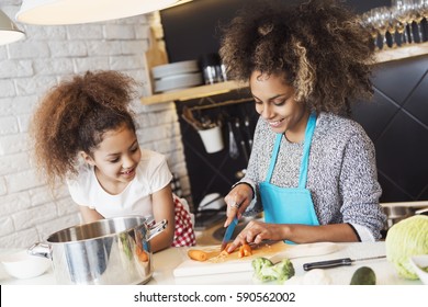 Beautiful African American woman and her daughter cooking in the kitchen 