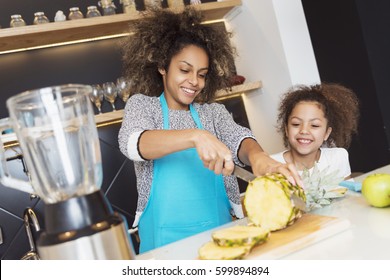 Beautiful African American woman and her daughter making a smoothie in the kitchen  - Powered by Shutterstock