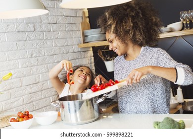 Beautiful African American Woman And Her Daughter Cooking In The Kitchen 