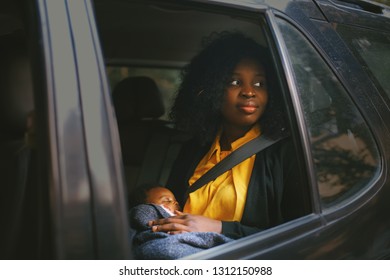 Beautiful African American Woman Holding A Baby In A Car Back Seat