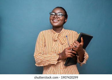 Beautiful African american woman holding files, laughing and looking up on a blue wall