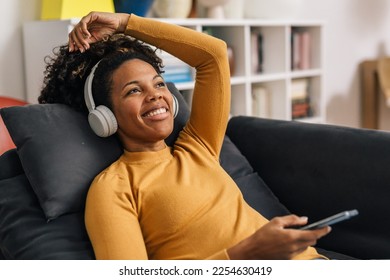 Beautiful African American woman is listening to music using headphones - Shutterstock ID 2254630419