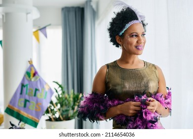 Beautiful African American Woman In Mardi Gras Costume Looking Through The Window At Home.