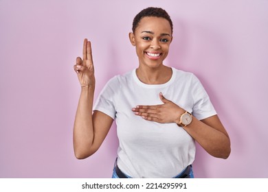 Beautiful African American Woman Standing Over Pink Background Smiling Swearing With Hand On Chest And Fingers Up, Making A Loyalty Promise Oath 