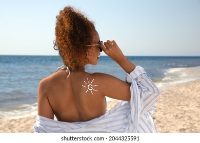 Beautiful African American Woman With Sun Protection Cream On Shoulder At Beach, Back View