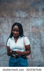 Beautiful african american woman using smartphone while out in the city with a marble wall in the background - Shutterstock ID 2019367646