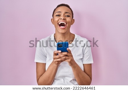 Beautiful african american woman using smartphone smiling and laughing hard out loud because funny joke. 