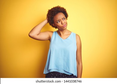Beautiful african american woman wearing elegant shirt over isolated yellow background confuse and wonder about question. Uncertain with doubt, thinking with hand on head. Pensive concept.
