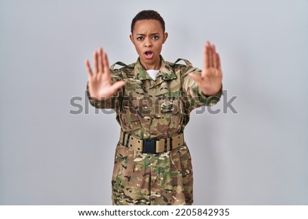 Beautiful african american woman wearing camouflage army uniform doing stop gesture with hands palms, angry and frustration expression 