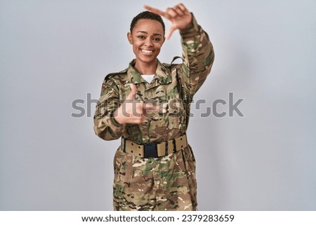 Beautiful african american woman wearing camouflage army uniform smiling making frame with hands and fingers with happy face. creativity and photography concept. 
