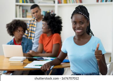 Beautiful african american young adult with dreads and group of students at classroom of university