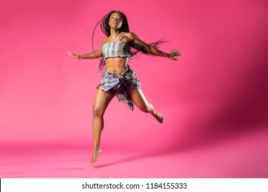 Beautiful African Black Girl Wearing Traditional Colorful African Outfit Does A Dramatic Dance Move Against A Colorful Pink Background