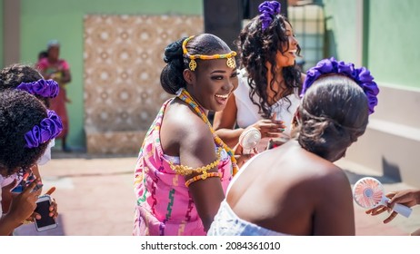 Beautiful African bride in kente cloth dancing happily with group of bridesmaids outdoor - concept on culture and marriage
