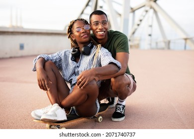 Beautiful African couple having fun outdoors. Portrait of an excited young couple with skateboard	
