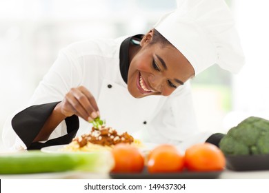 beautiful african female chef garnishing spaghetti dish - Powered by Shutterstock