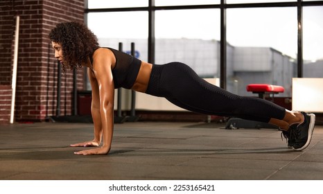 Beautiful african fitness woman doing push ups during cross training in fitness studio - Powered by Shutterstock