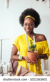 Beautiful African Girl Smiling Holding Flower Pot In Hands